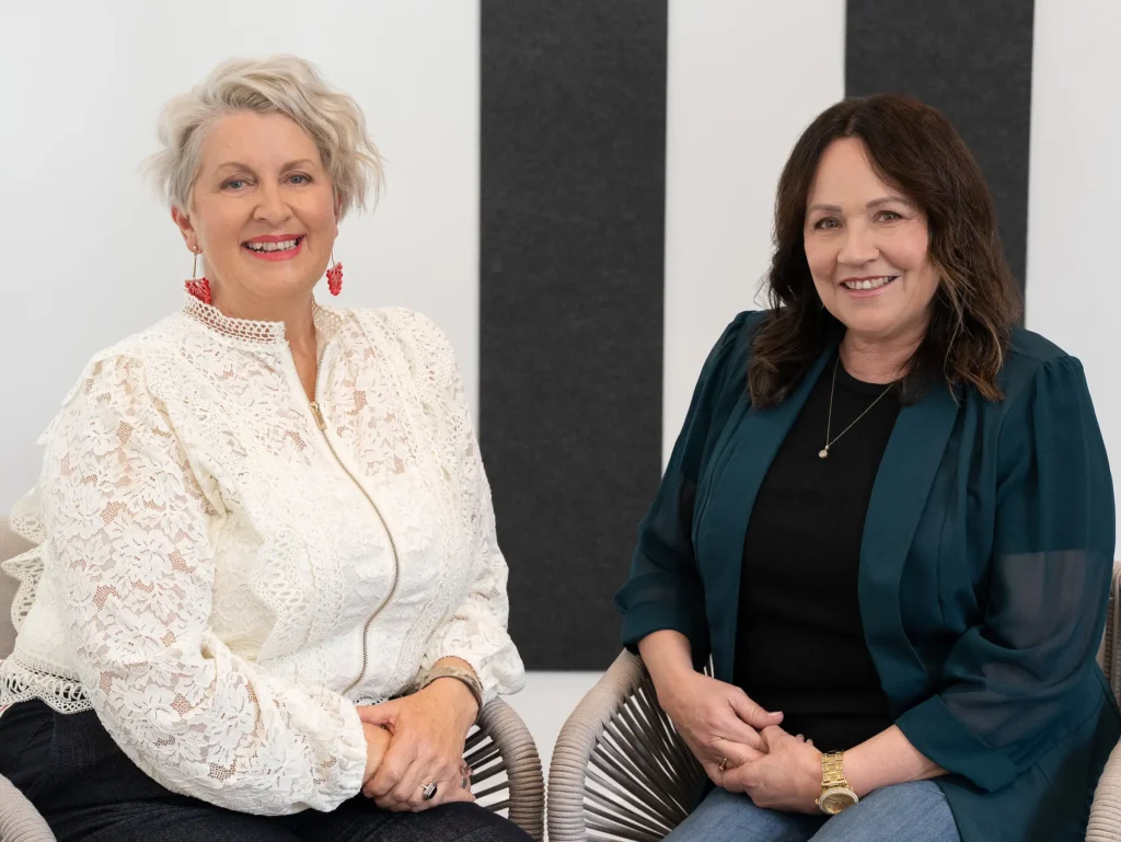Two HerZest members seated together, smiling